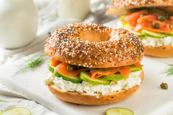 sandvisuri cu bagel, castraveti, capere, somon si crema de branza pe un platou alb