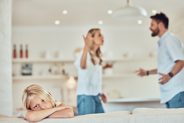 fetita deprimata pe canapea in timp ce parintii ei se cearta