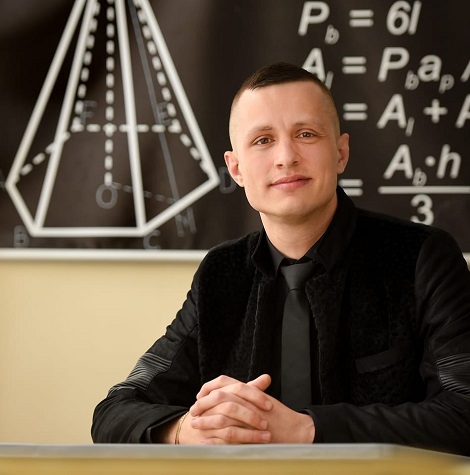 profesorul de matematica Madalin Ghiuler langa o tabla pe care se vede o problema de geometrie