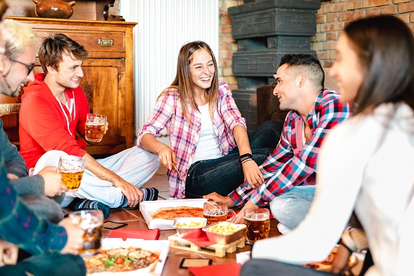 grup de adolescenti care s-au reunit ca sa manance pizza acasa