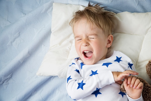 baietel in pijama alba cu stelute albastre tipand in somn