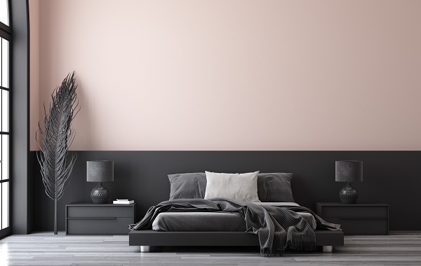 dormitor cu un pat gri si cu peretele vopsit in doua culori, roz si gri