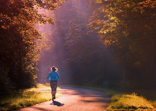 femeie care face jogging in natura, profitand de lumina diminetii
