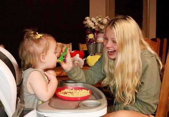 Maddie Lambert fericita in timp ce isi hraneste fiica