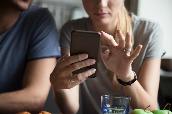 femeie tânara care umbla cu telefonul in timp ce se afla langa partenerul ei