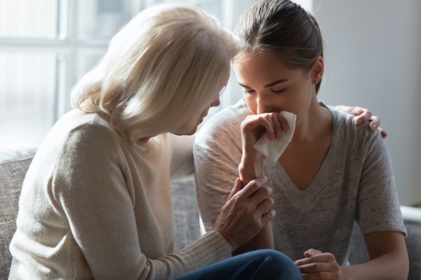 femeie tânara deprimata, care plange si este consolata deo femeie matura