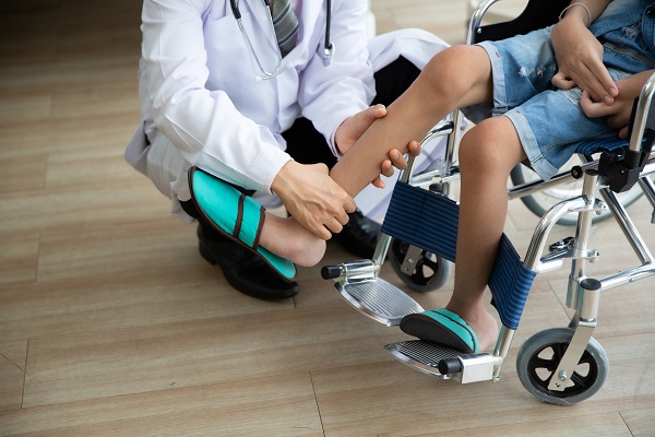 medic care examineaza picioarele unui baietel aflat in scaunul cu rotile