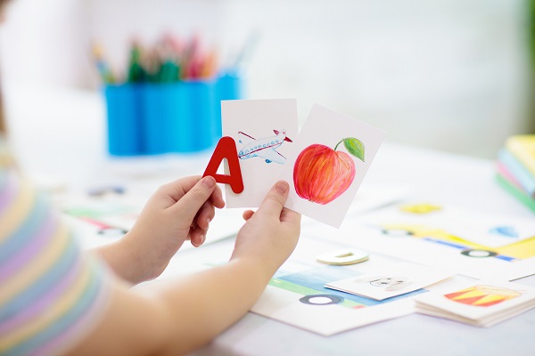 copil care invata literele cu ajutorul unor flash-carduri colorate cu litere si cu cuvinte care incep cu litera respectiva