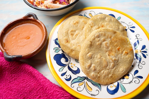 pupusas puse pe o farfurie, alaturi de care se afla sosul de rosii