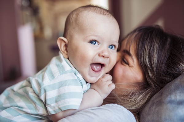 mama vesela care sta intinsa pe canapea si si-a facut bebelusul sa râda