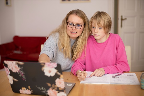 femeie blonda cu ochelari care îi arata ceva in laptop unei adolescente care isi ia notite