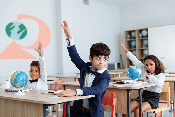 elevi care ridica mâna in sala de clasa