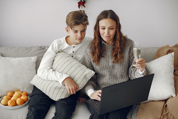 mama zambitoare care se uita pe laptop alaturi de fiul ei adolescent