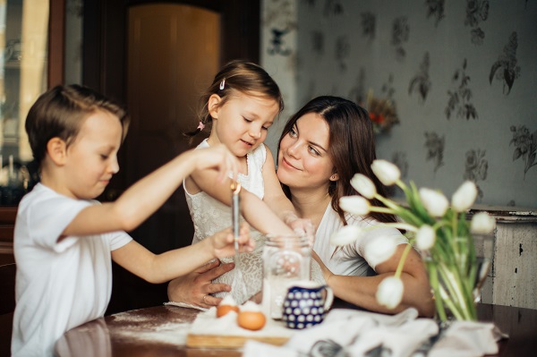 mama vesela alaturi de cei doi copii ai ei care sunt implicati in activitati de gatit