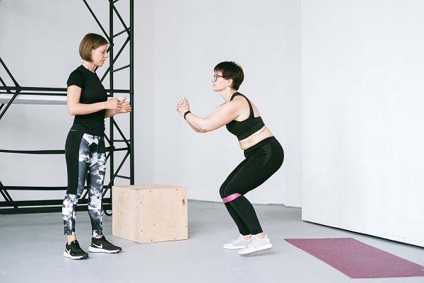 femeie tanara antrenor de fitness care îi da instructiuni referitoare la exercitiu unei femei mature