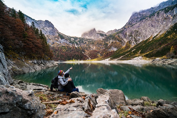 cuplu stand pe marginea unui lac la munte