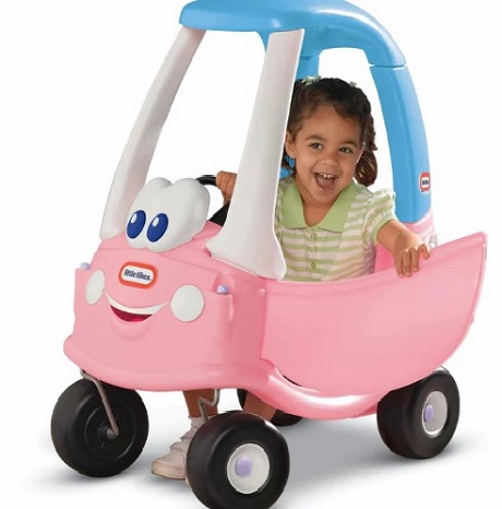 fetita conducandu-si masinuta Cozy Coupe cu roz, alb si albastru
