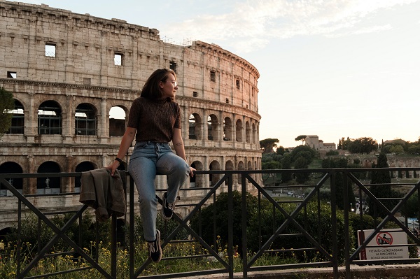 femeie tanara stand pe un gard si admirand Colosseum, in  Roma