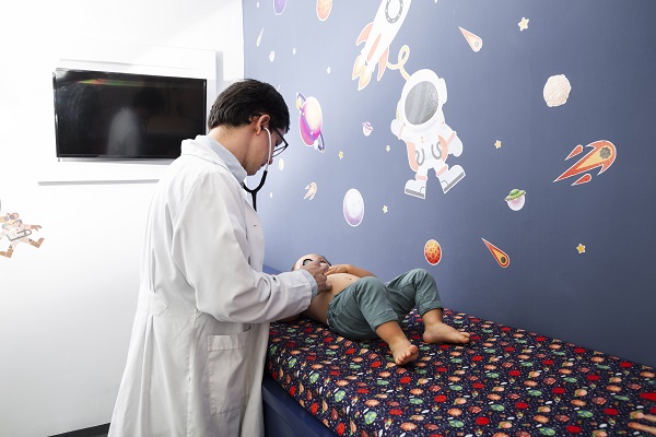 medic consultand un bebelus intins pe pat