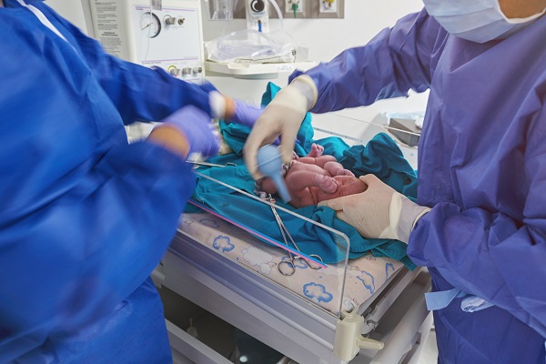 cadre medicale care curata un nou-nascut in sala de nasteri