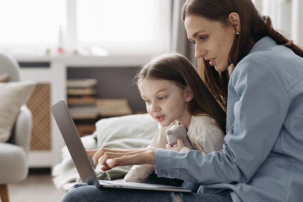 mama si fetita ei se uita impreuna pe laptop