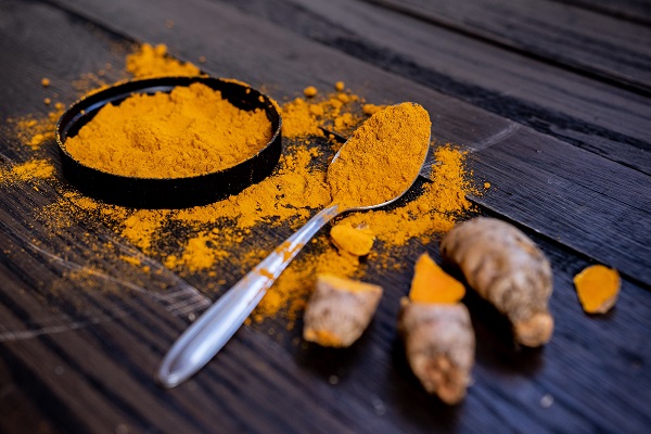 vas cu pulbere de turmeric, lingurita cu pulbere de turmeric si turmeric proaspat