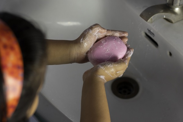 fetita care se spala pe maini cu un sapun roz