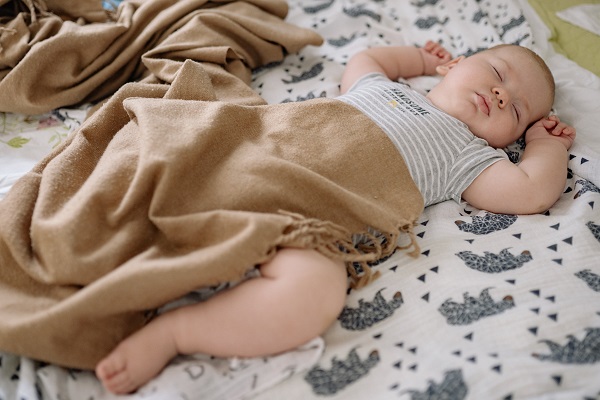 bebelus care doarme cu un piciorus dezvelit