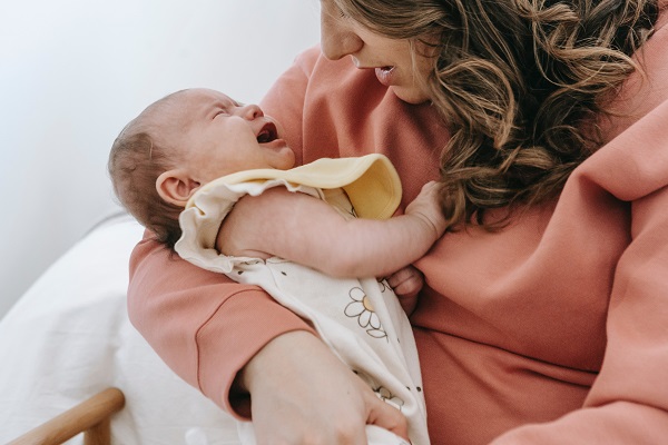 mama care incearca sa isi liniteasca fetita care plange tinand-o in brate