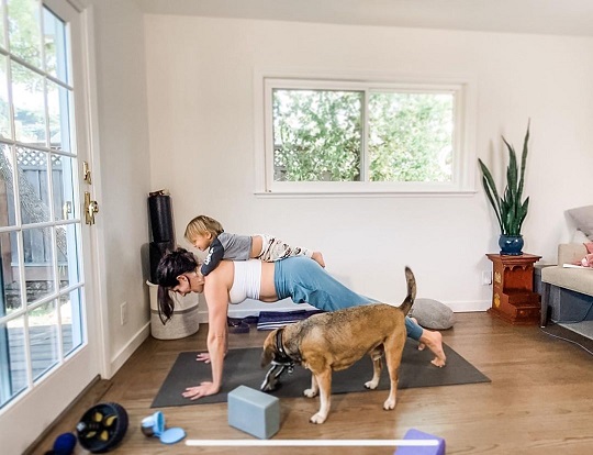 femeie ce practica yoga acasa, alaturi de copilul ei