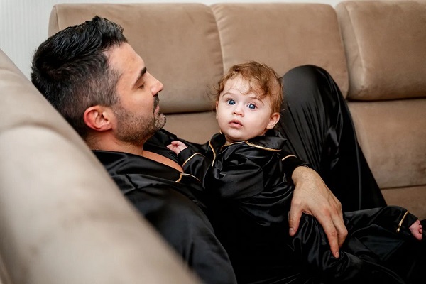 Pepe si fiul lui stand pe canapea, amandoi purtand pijamale negre