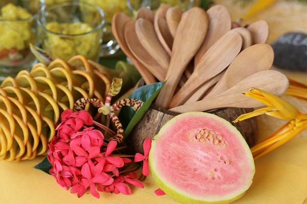 guava cu miez roz, alaturi de flori exotice si lingurite de lemn