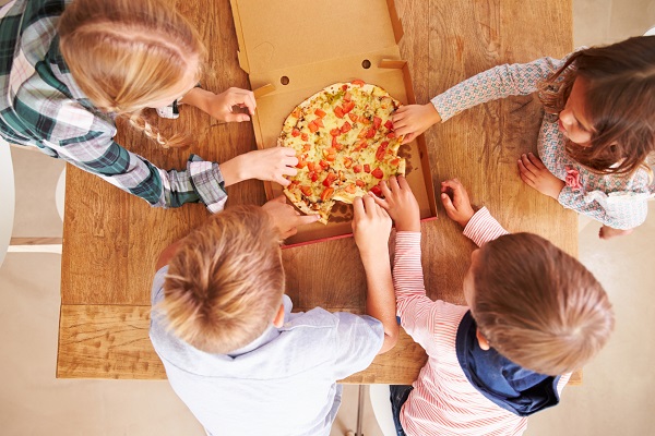 copii care se pregatesc sa imparta o pizza