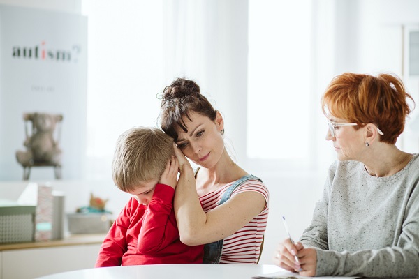 mama trista ce isi tine in brate baietelul, in timp ce asteapta opinia unui specialist in tulburari de spectru autist