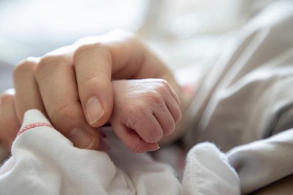 mână de femeie care ține pumnul unui bebelus prematur