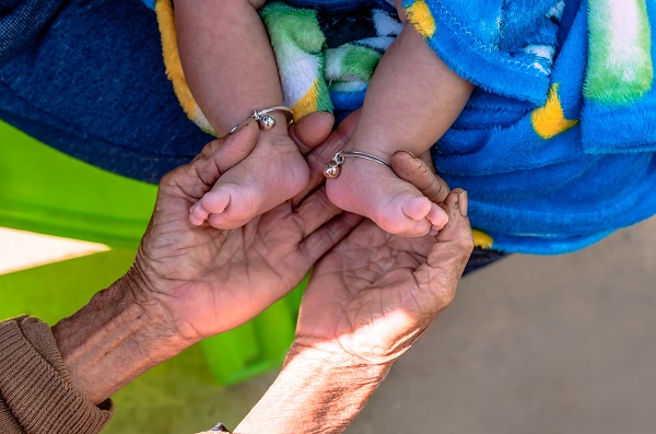 mainile unei femei in varsta apucand talpitele unui bebelus