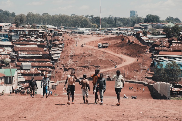 grup de baieti africani trecand printr-o suburbie a unui oras african