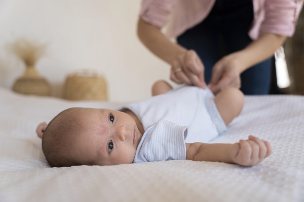 mama care incheie sau deschie capsa de la body-ul bebelusului ei