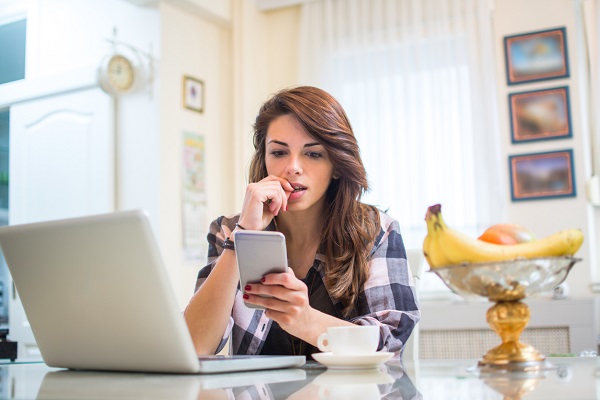 femeie tanara, ingrijorata, care se uita pe telefon