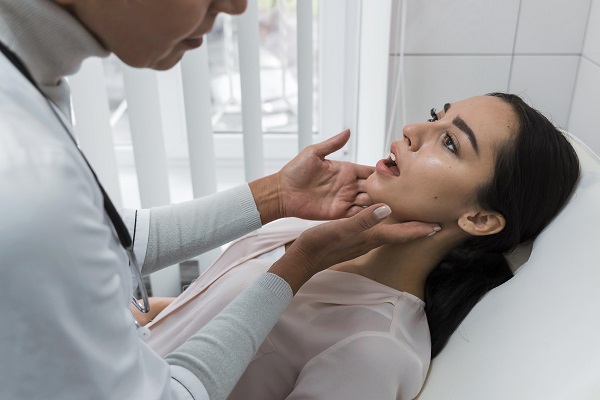 doctorita care controleaza cavitatea bucala a unei paciente in timpul unei consultatii