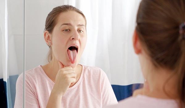 femeie care isi examineaza limba la oglinda