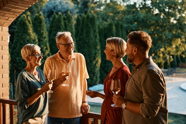 cuplu de seniori si cuplu tanar care petrec timp impreuna savurand un pahar de vin 