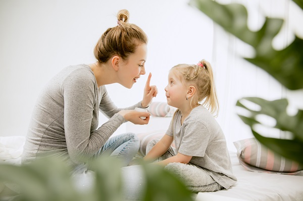 mama care incearca sa îi atraga atentia fiicei sale, într-un mod cat mai blând, in timpul unei conversatii acasa