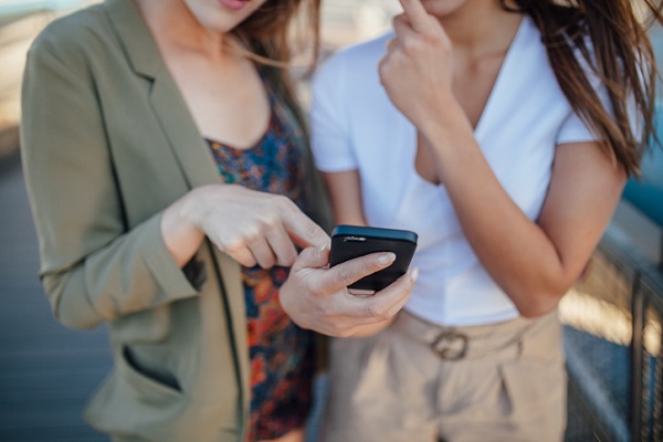 femeie care îi arata ceva pe telefon unei alte femei