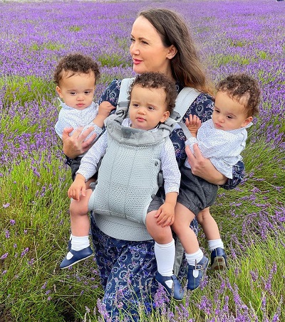 mama fericita plimbandu-se pe un camp de lavanda impreuna cu tripletii ei