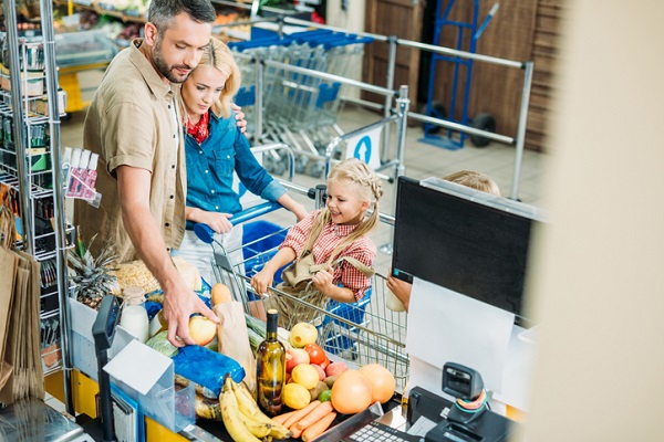 cuplu fericit cu copiii lor la casa de marcat la un supermarket