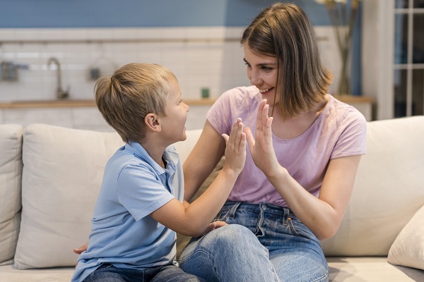 mama vesela care bate palma cu baietelul ei fericit