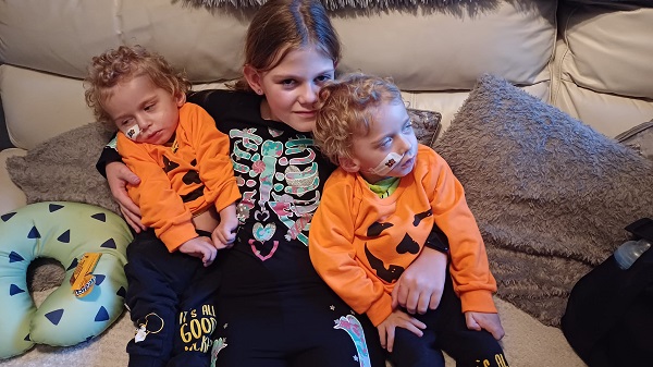 fetita care are grija de fratiorii ei gemeni bolnavi, imbracati in costume de Halloween