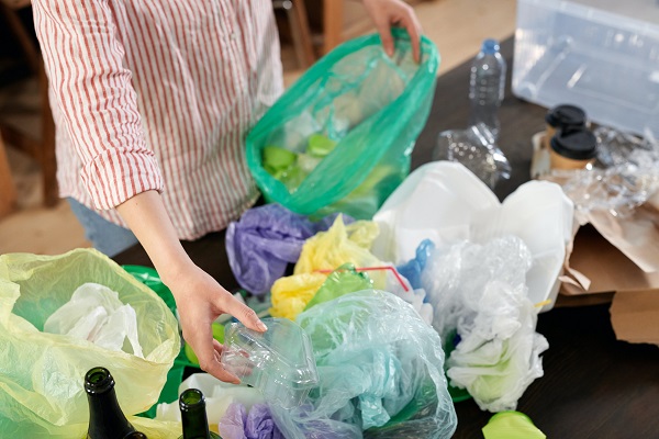 femeie care colecteaza diverse deseuri in pungi de plastic