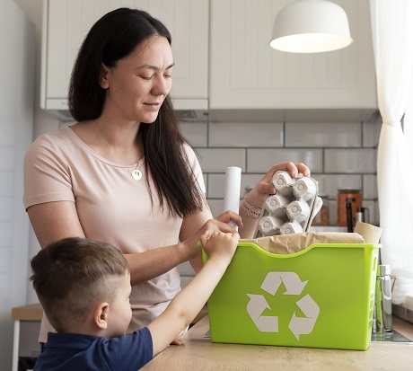 baietel care isi ajuta mama sa sorteze diferite deseuri de hartie si carton acasa